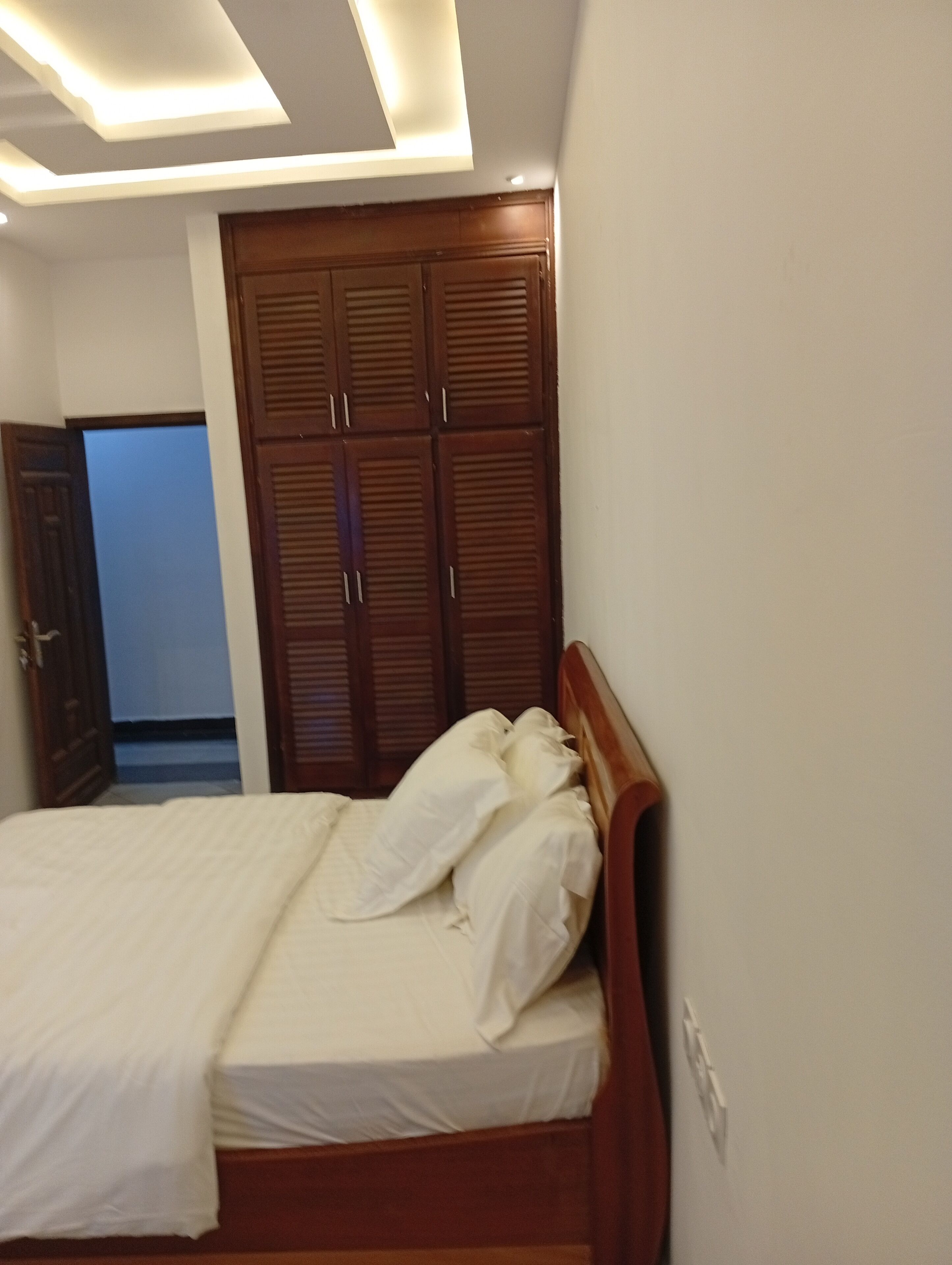 Un dormitorio con una cama, un armario de madera y una puerta que da a otra habitación.