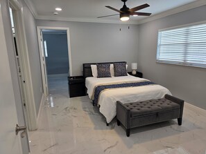 Une chambre Ă coucher avec un lit, une table de chevet, une lampe et un ventilateur de plafond.