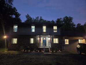 A two-story house with a front porch, a garage, and a driveway. - Poconos Group Getaway: Hot Tub, Fire Pit & Pet Friendly (Lakeville)