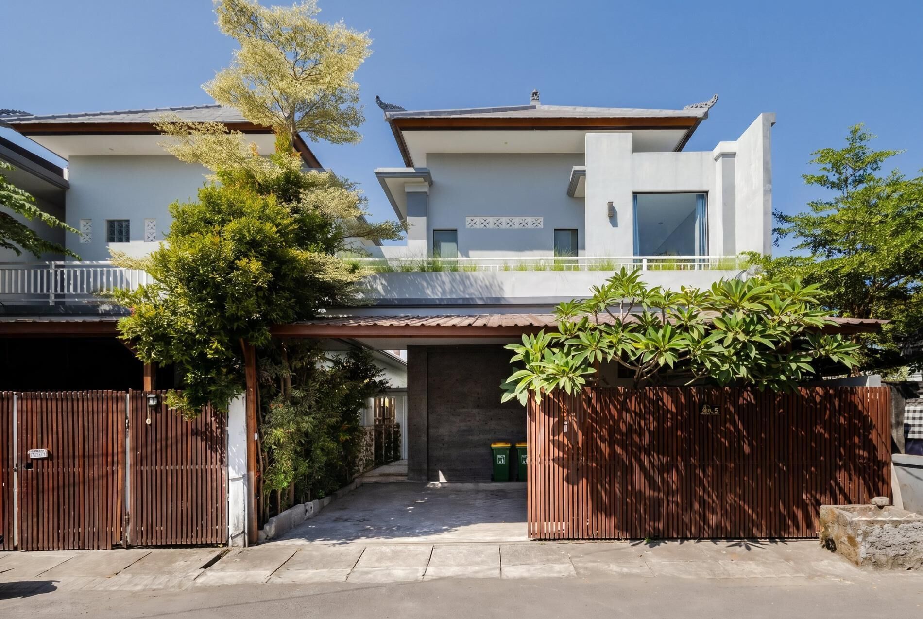 Une maison moderne à deux étages, dotée d’une allée couverte, d’une entrée sécurisée par un portail et d’un petit jardin.
