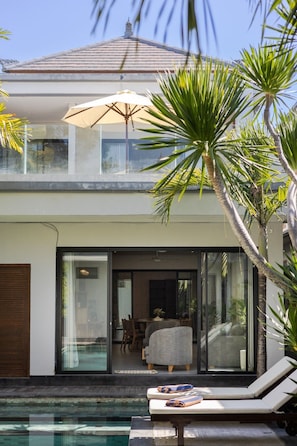 Ein modernes Haus mit Pool, Essbereich und einer Lounge mit Sessel und Tisch.