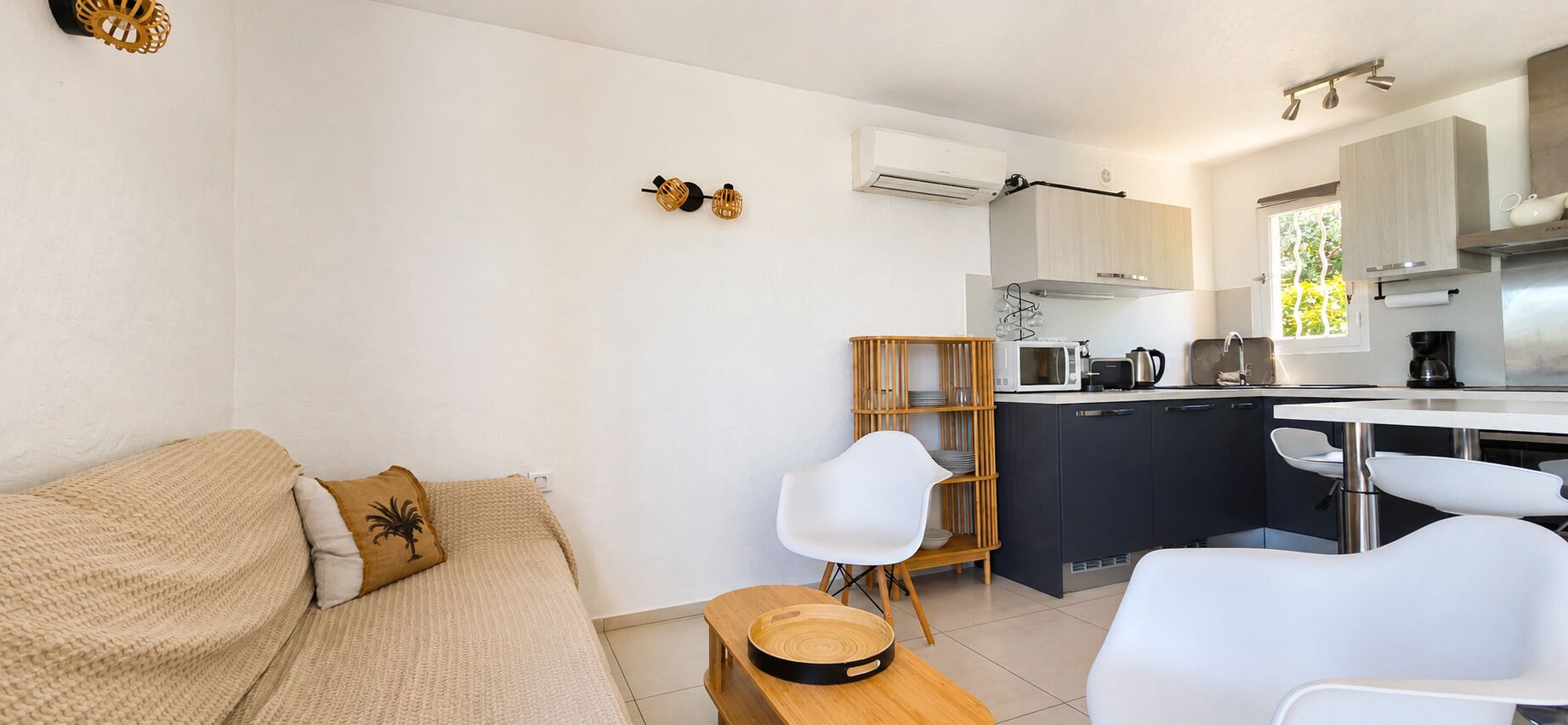 Una cocina moderna con microondas, hervidor y cafetera. Hay una mesa de comedor de madera con sillas.