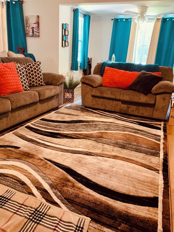 A living room with two sofas, a patterned rug, and a ceiling fan.