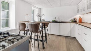 A modern kitchen with white cabinets, a wooden countertop, and a gas stove. - 4 Star Holiday Home in Spottrup (Spøttrup)