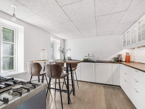 A modern kitchen with white cabinets, a wooden countertop, and a gas stove. - 4 Star Holiday Home in Spottrup (Spøttrup)