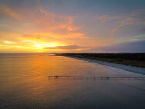A coastal sunset view with a beach and a pier. - 4 Star Holiday Home in Strandby (Strandby)