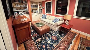 Una sala de estar con sofá, reposapiés y una estantería.