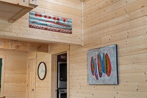 A wooden interior with a sign reading 'BOTT for Hire' and a painting of colorful fish hooks. - Authentic Log Cabin w Private Hot Tub_Near Big Cedar & Thunder Ridge_Free Tickets_Bonus Loft (Ridgedale)