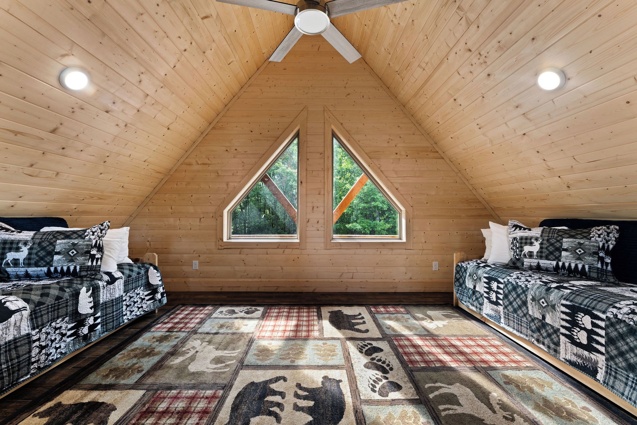 A high-ceilinged room with two beds, a large window, and a ceiling fan.