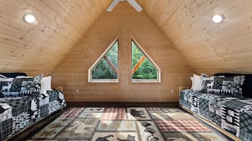 A high-ceilinged room with two beds, a large window, and a ceiling fan.