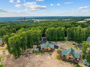 Oversigtsbillede af et resort med flere bygninger, en grusvej og omkringliggende skov.