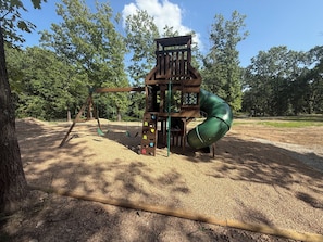 A playground with a wooden play structure, including a slide and climbing elements. - Authentic Log Cabin w Private Hot Tub_Near Big Cedar & Thunder Ridge_Free Tickets_Bonus Loft (Ridgedale)