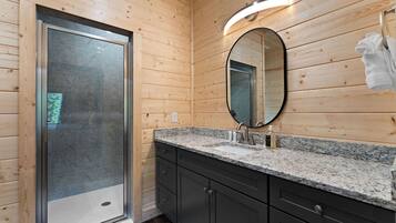 A modern bathroom with a shower, a sink with a mirror, and wooden walls.