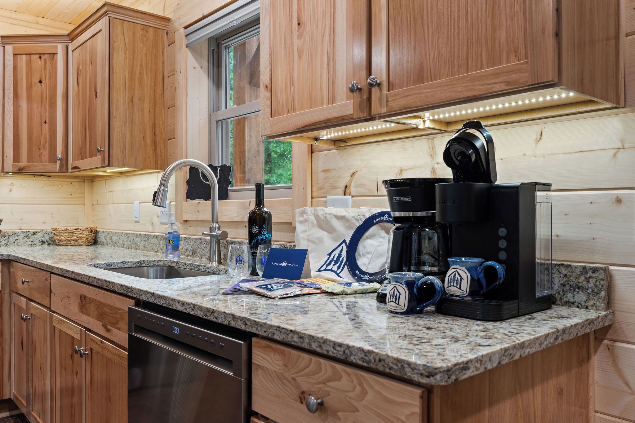 A kitchen with wooden cabinets, a granite countertop, a coffee maker, and a dishwasher.