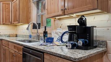 A kitchen with wooden cabinets, a granite countertop, a coffee maker, and a dishwasher.