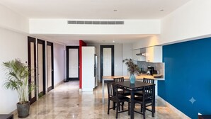 A modern kitchen with a dining area, a potted plant, and a blue accent wall. - Deck12 2BR Premium Pool Access Parking (Puerto Vallarta)