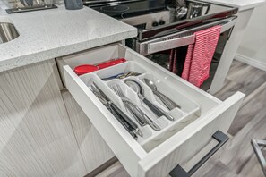 A kitchen drawer with utensils and a red lid. - Cozy Kensington Suite | Sleeps 6 | 1BR + Sofa Bed (Calgary)