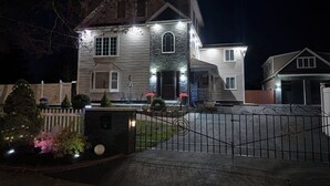 Uma casa de dois andares com fachada de pedra, varanda frontal e entrada com portão.