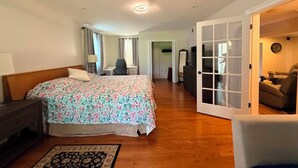 Quarto com cama, mesa de cabeceira e vista para a sala de estar.
