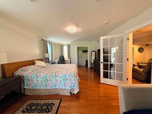 Ein Schlafzimmer mit Bett, Nachttisch und Blick in den Wohnbereich.