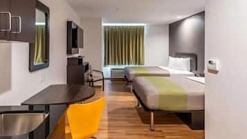 Una habitación de hotel con cama, escritorio, silla, televisor y ventana con cortinas.