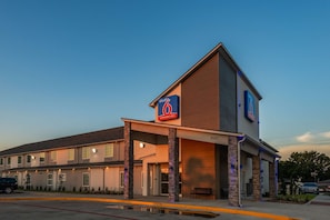 Um motel com estrutura de dois andares, entrada coberta e placa indicando que oferece estadias prolongadas.