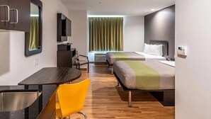 Une chambre d’hôtel moderne équipée d’un lit, d’un bureau, d’une chaise, d’un miroir et d’une fenêtre avec des rideaux.