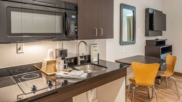 Une cuisine moderne équipée d’un four à micro-ondes, d’une cuisinière, d’un évier et de chaises jaunes.