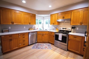 A modern kitchen with wooden cabinets, stainless steel appliances, and a tiled backsplash.