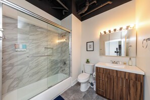 Ein modernes Badezimmer mit einer Duschkabine, einer Toilette, einem Waschtisch inklusive Spiegel und Waschbecken.