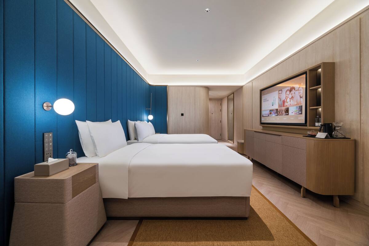 Una habitación de hotel moderna con una cama grande, televisión, escritorio y armario empotrado.