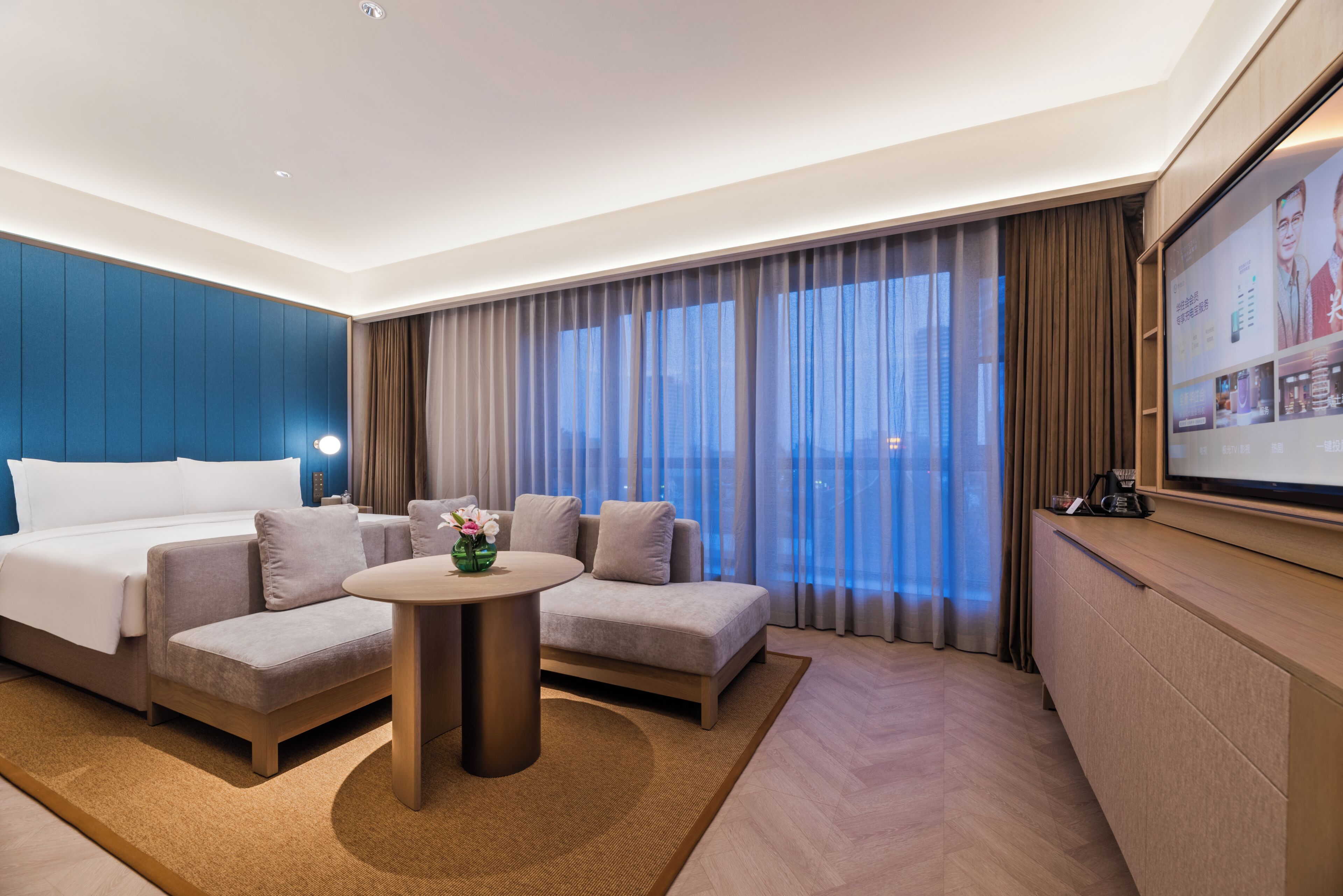 Una habitación de hotel moderna con cama, sofá y una pequeña mesa.