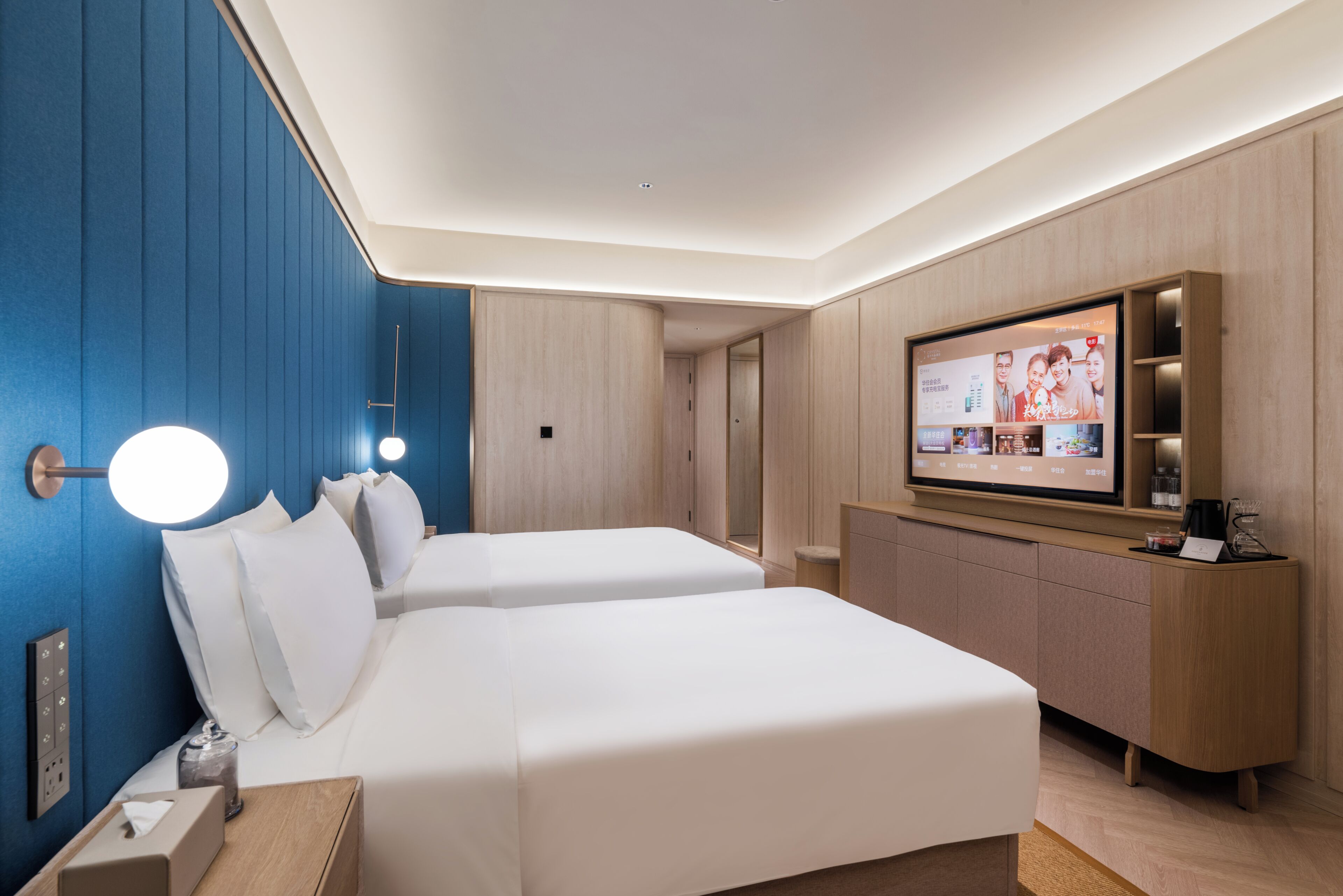 Een hotelkamer met twee bedden, een televisie, een bureau en een minibar.