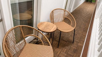 Een gang met een patroon vloer, twee rieten stoelen en een glazen deur.