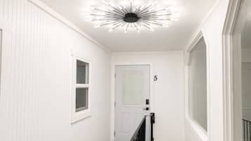 Een gang met witte wanden, een zwarte balustrade en een plafondlamp.