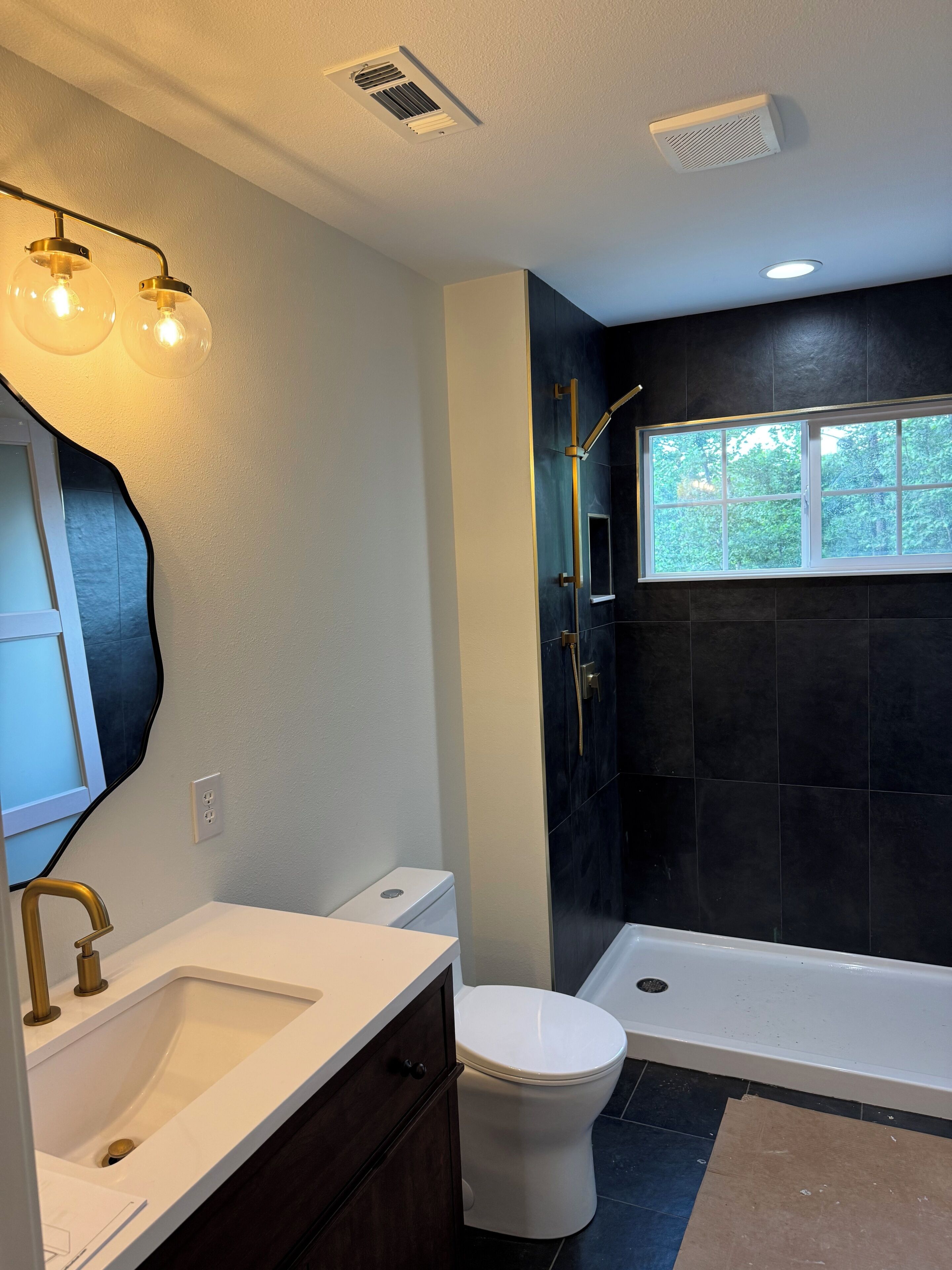 A modern bathroom with a white sink, a toilet, a bathtub, and a shower. There is a window providing natural light and a mirror above the sink.. Newly renovated 3 bedroom 2 full bathroom secluded cabin.