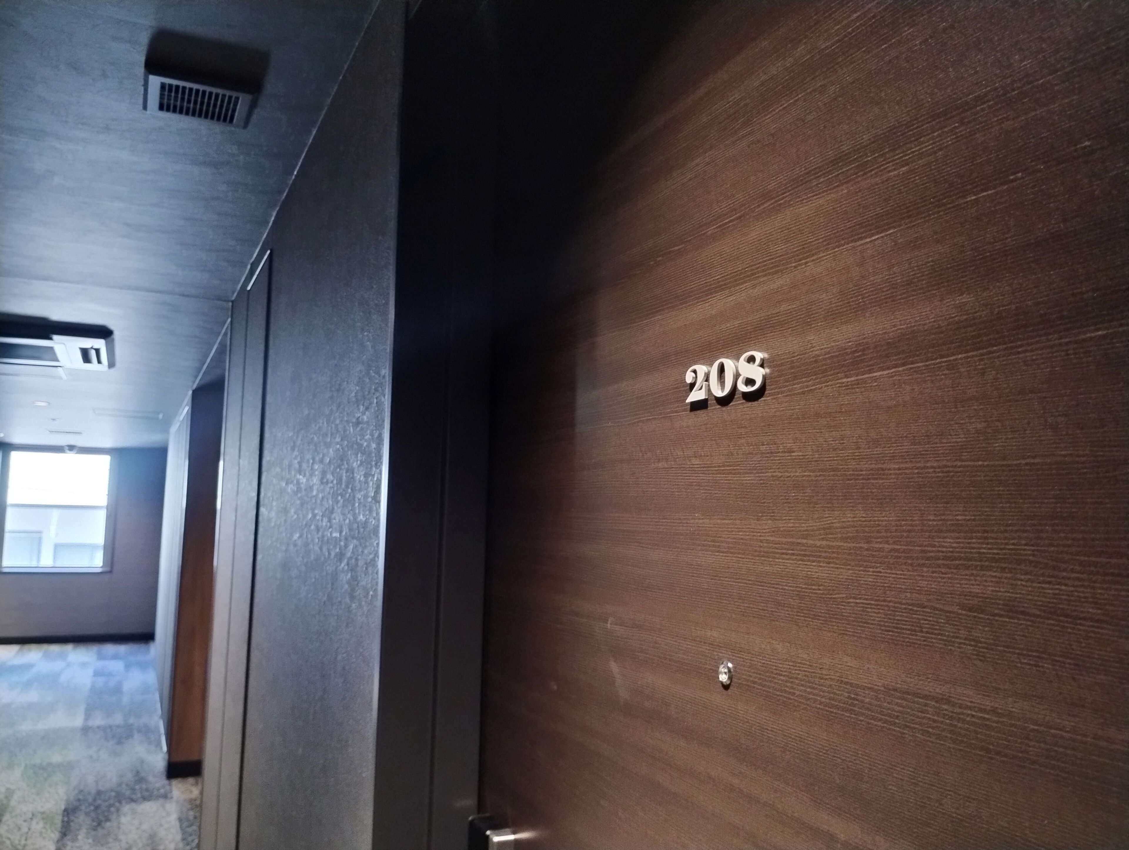 Una puerta de madera con el número '208' y un picaporte metálico.