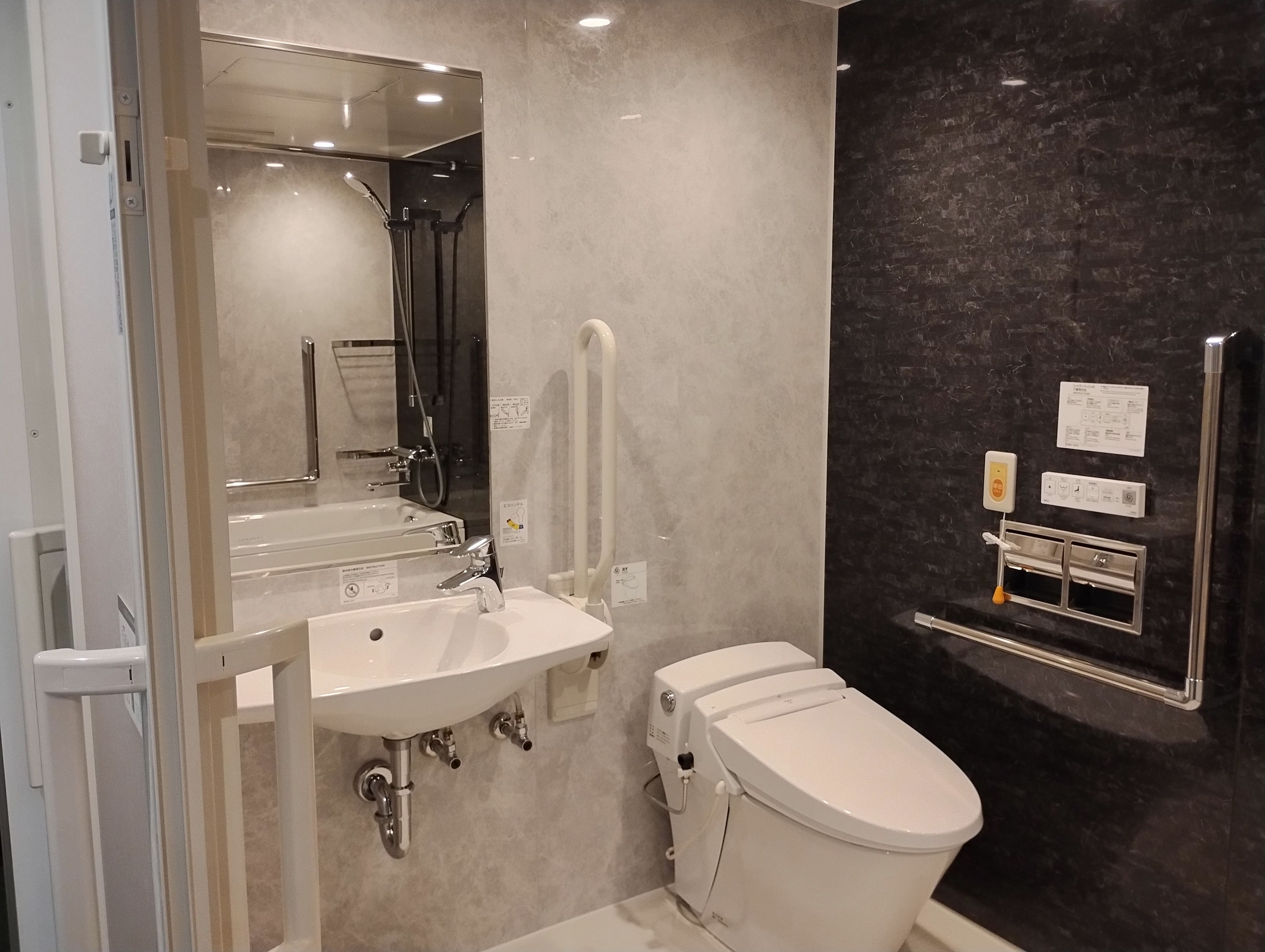 A modern bathroom with a sink, mirror, toilet, and a towel rack.
