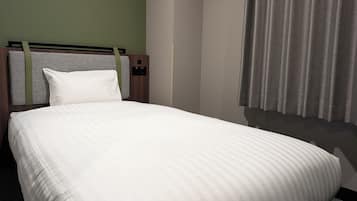 Habitació d'hotel amb un llit, capçalera i cortines.