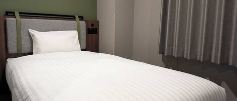 Una habitación de hotel con cama, cabecera y cortinas.