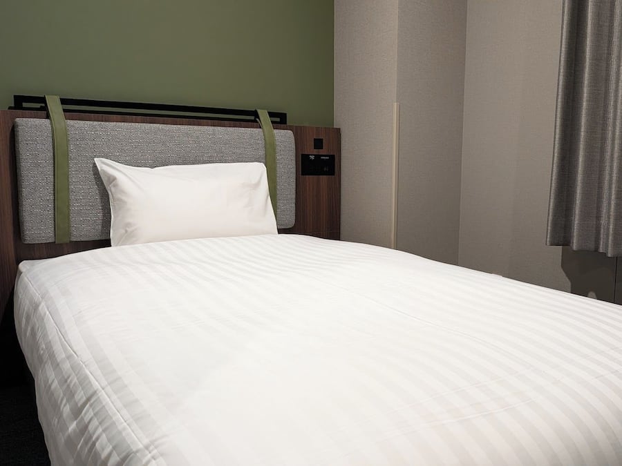 A hotel room with a bed, headboard, and curtains.