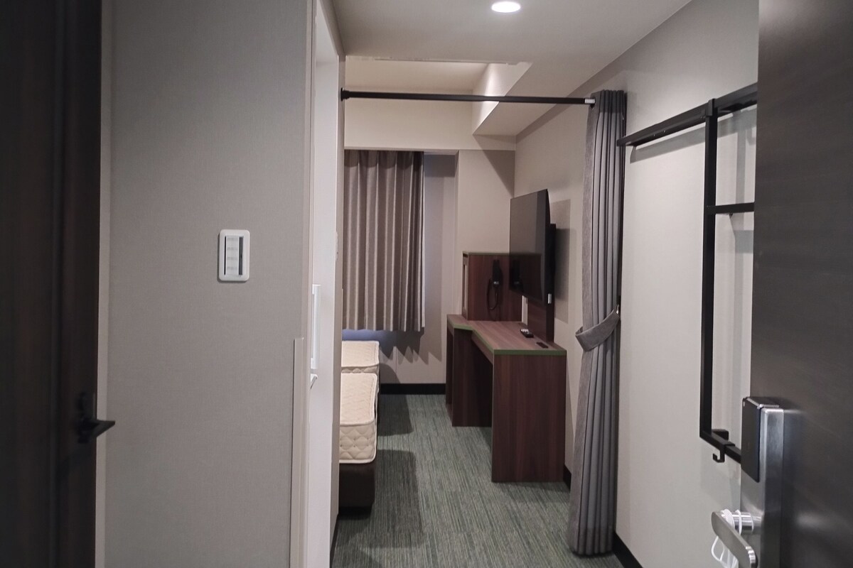 Ein Hotelzimmer mit Bett, Schreibtisch, Fernseher und Bad.