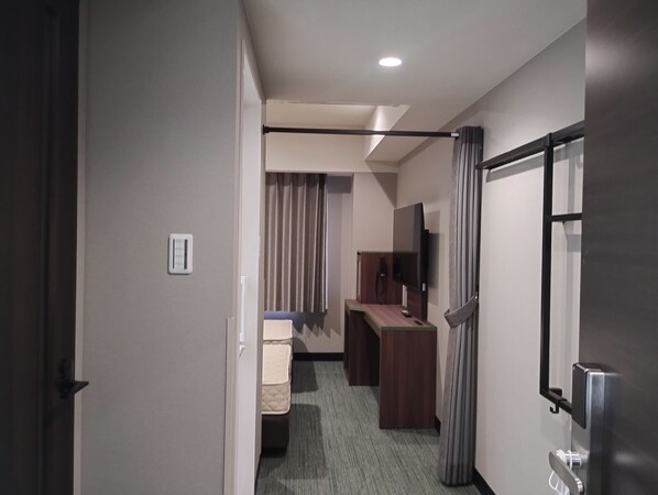 Ein Hotelzimmer mit Bett, Schreibtisch, Fernseher und Bad.