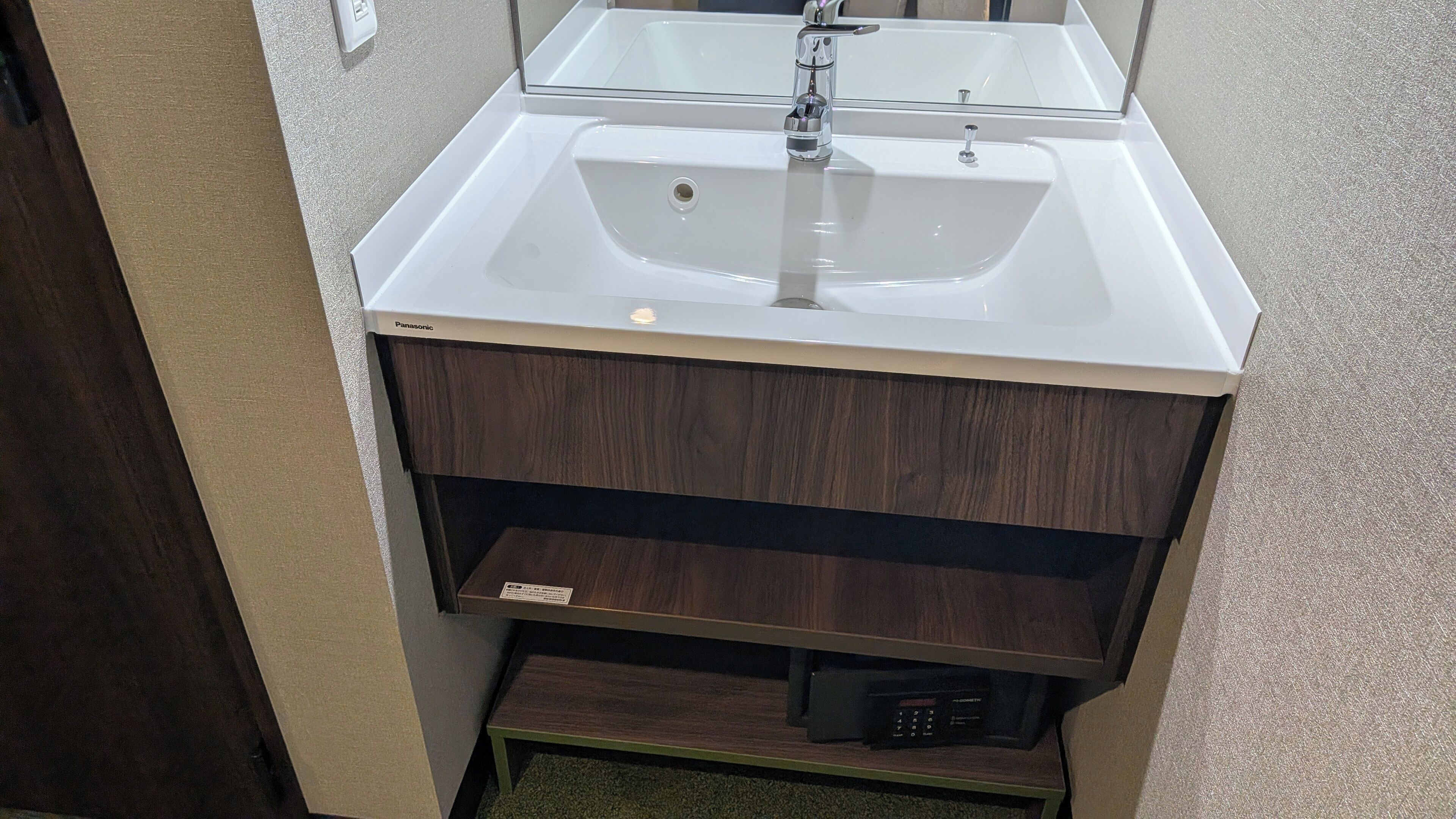 Ein Badezimmer mit einem weißen Waschbecken, einem Spiegel darüber und einer Holzausstattung darunter.
