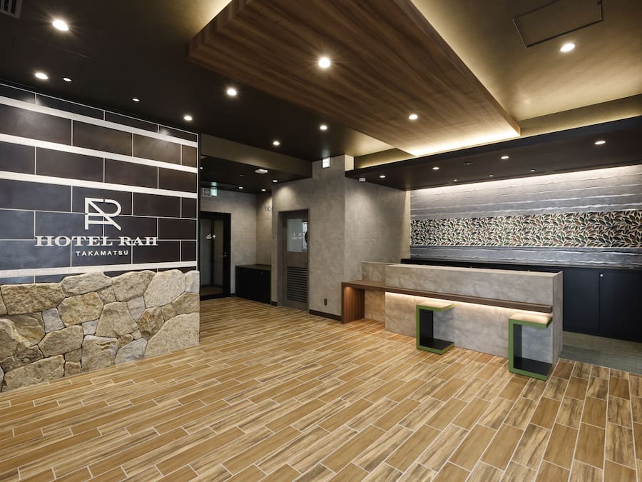Zona de recepción de un hotel con pared de piedra, mostrador y diseño moderno de techo.
