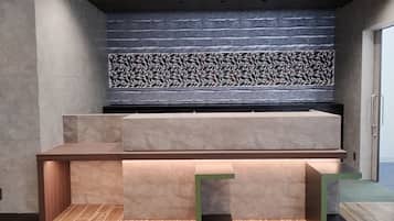 Un mostrador de recepción de diseño moderno, una pared con un estampado llamativo detrás y una cámara de seguridad en el techo.
