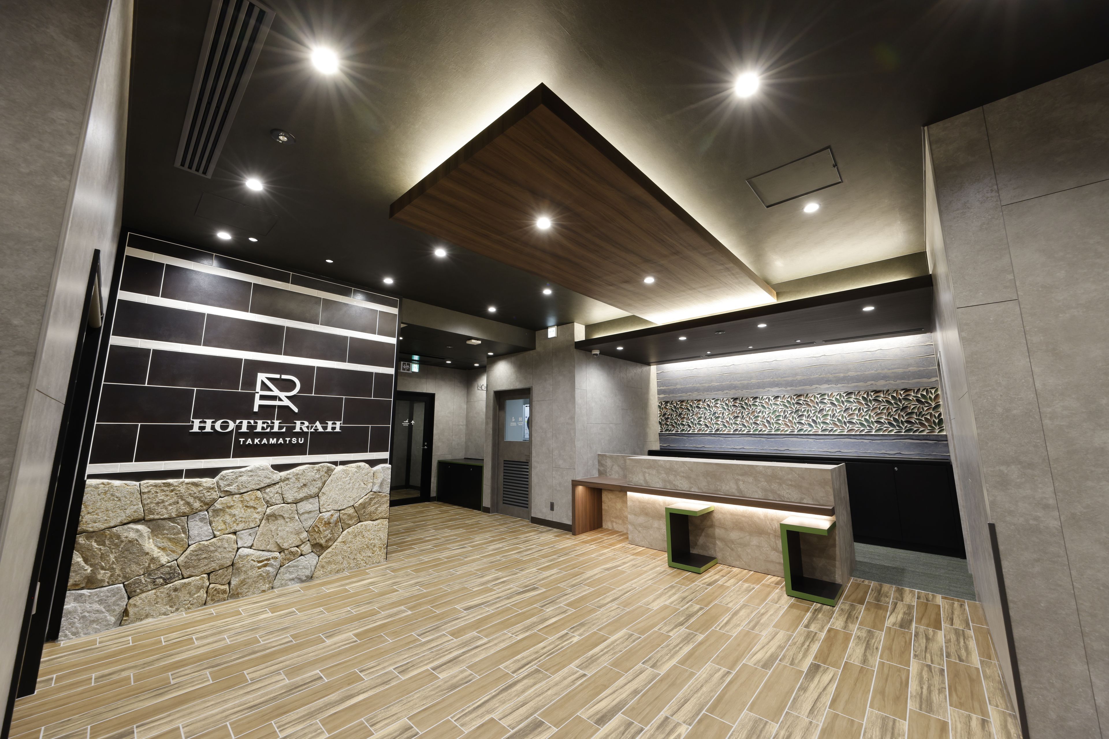 Un vestíbulo de hotel moderno con pared de piedra, mostrador de recepción y techo de madera.