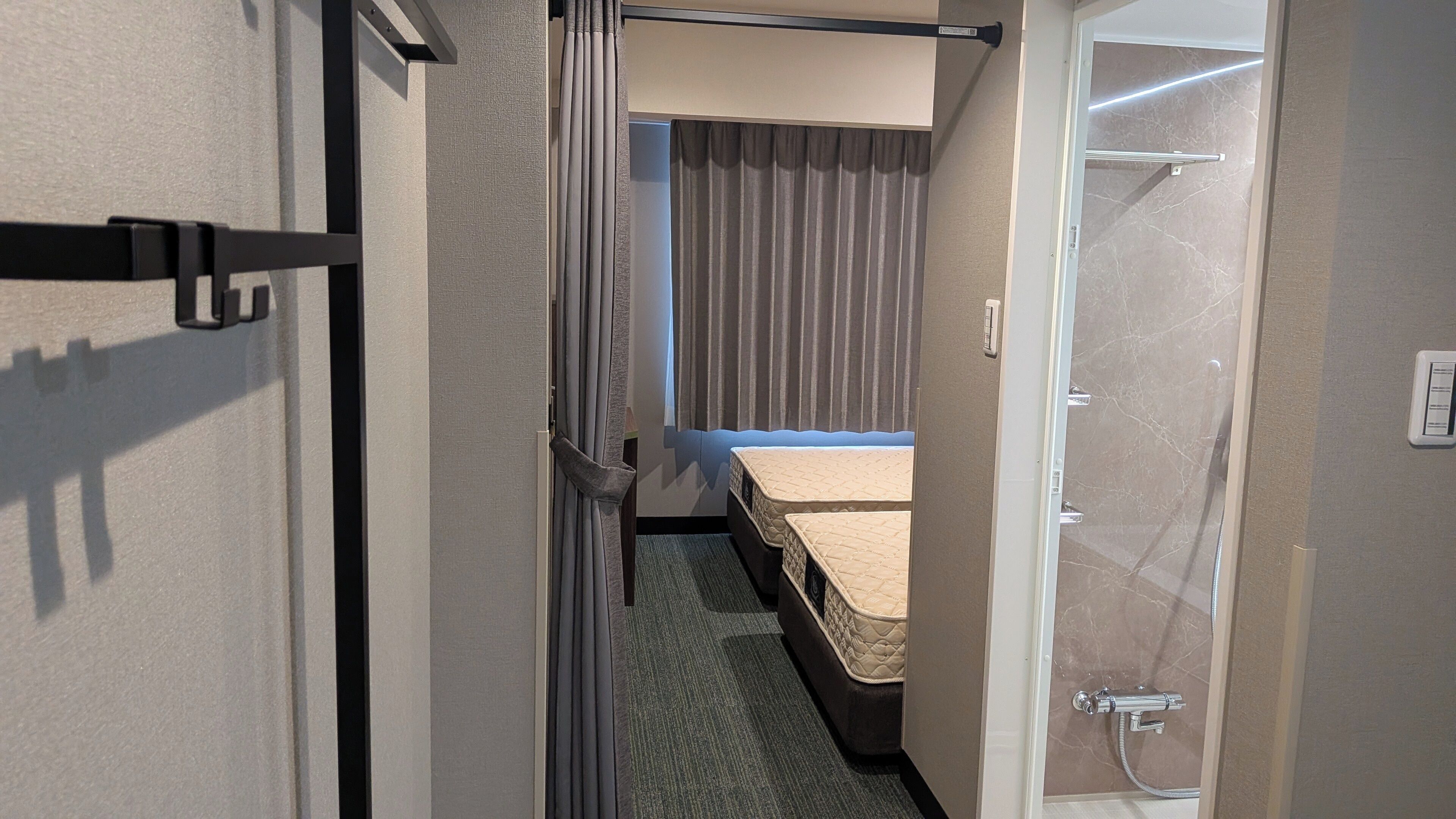 A hotel room with a bed, a shower, and a curtain.