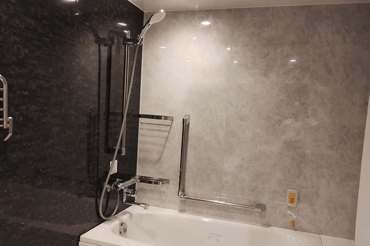 Ein modernes Badezimmer mit einer Badewanne, einer Dusche und einer Haltestange.