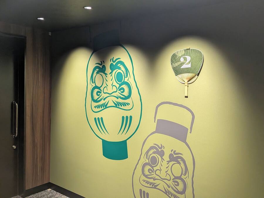 A wall with a large, stylized face and a number '2' in a hanging lantern.